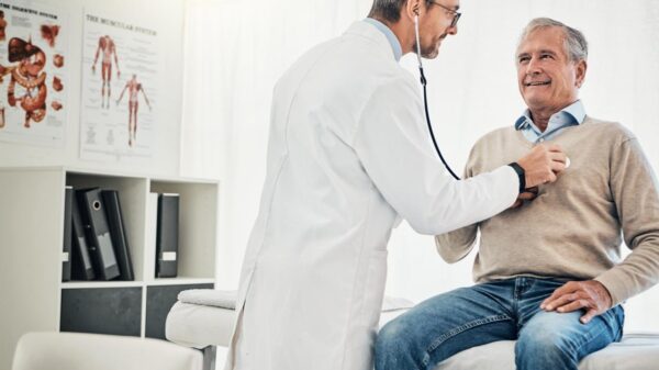 Homem no consultório com um médico o examinando com estetoscópio.