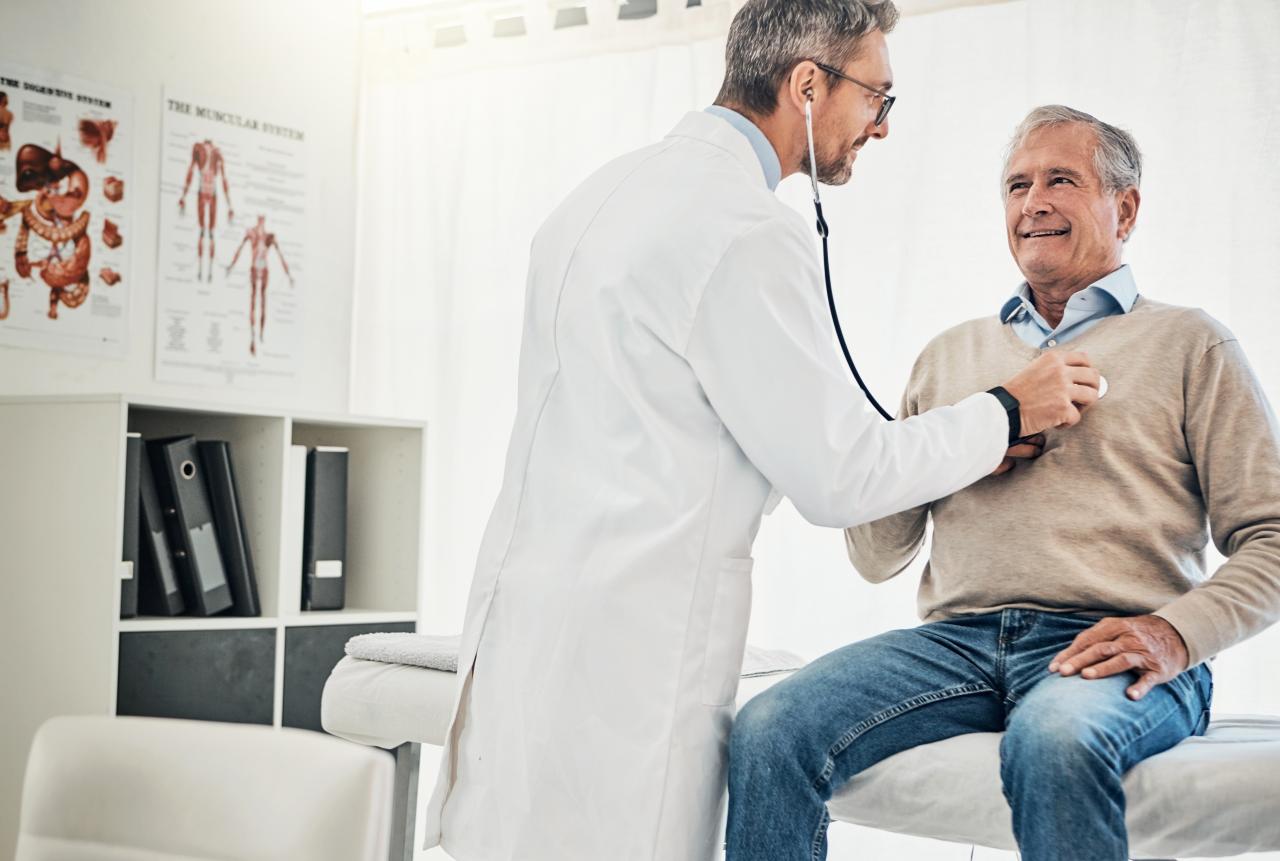 Homem no consultório com um médico o examinando com estetoscópio.