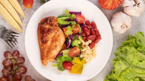 Um prato com vários alimentos saudáveis dentro e em cima da mesa ao lado.