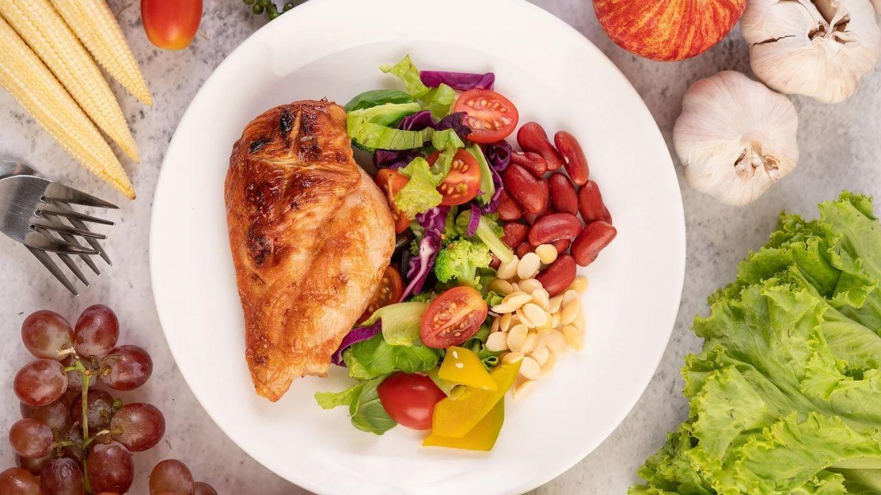 Um prato com vários alimentos saudáveis dentro e em cima da mesa ao lado.
