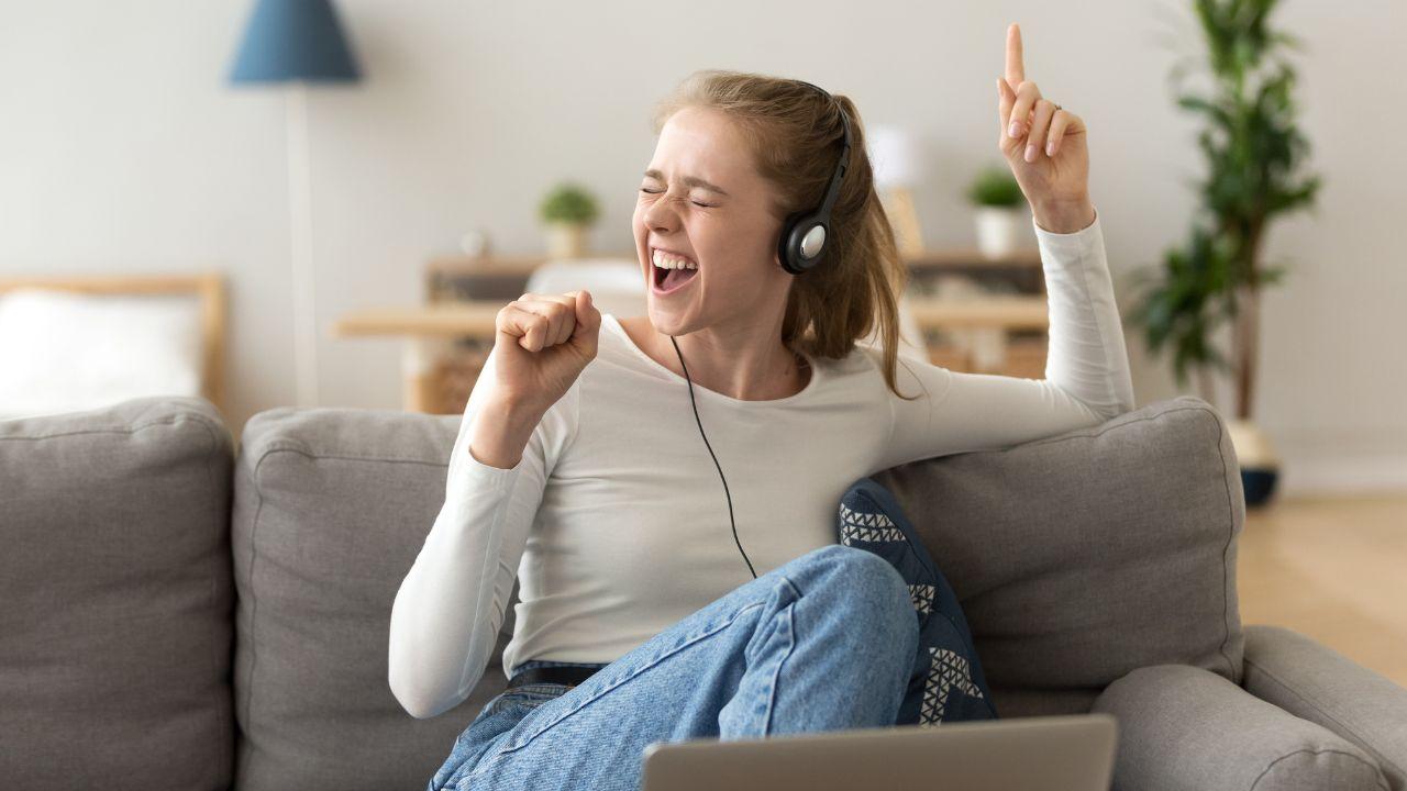 Imagem de uma jovem cantando com fone de ouvido