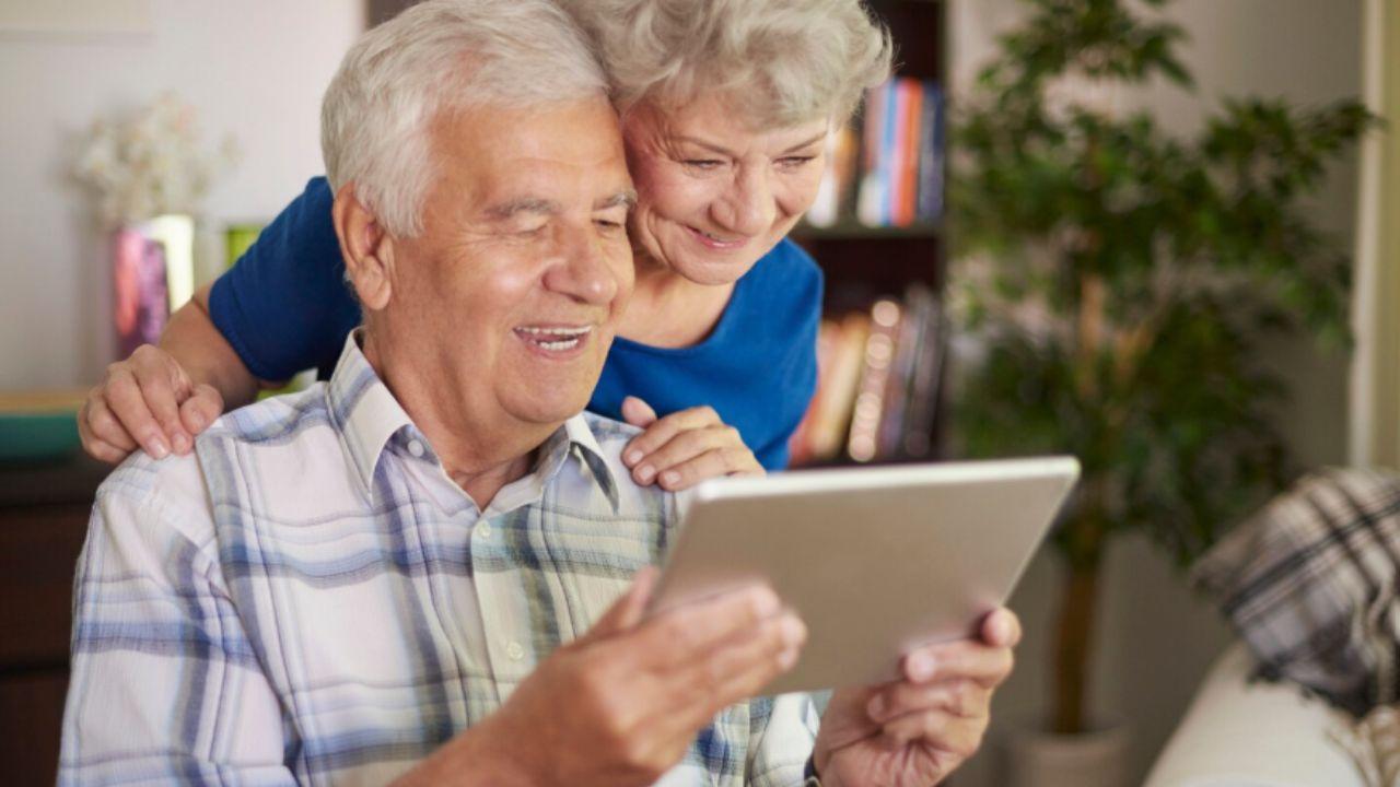 Homem e mulher idosos mexendo em um tablet.