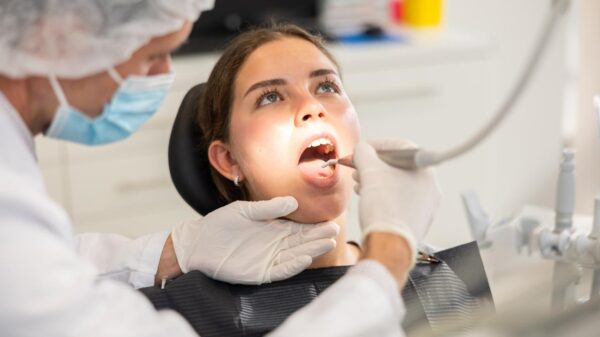 Mulher sentada no consultório do dentista com a boca aberta.