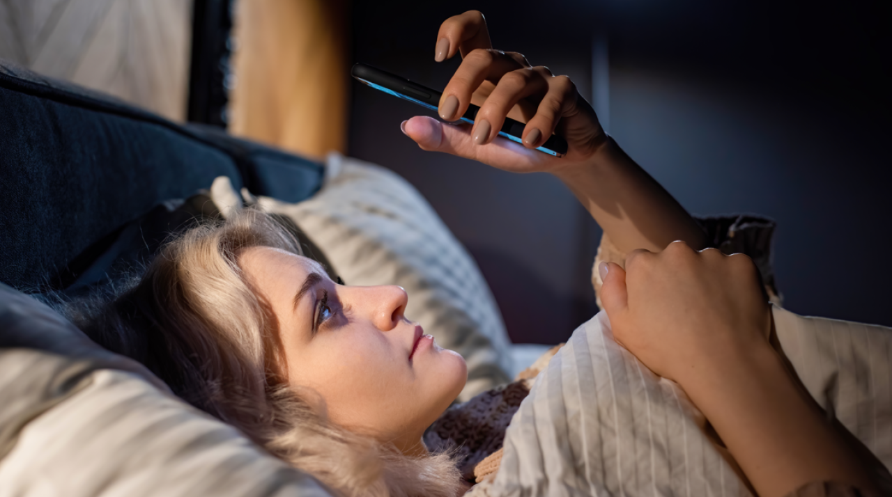 Mulher com celular pouco antes de dormir